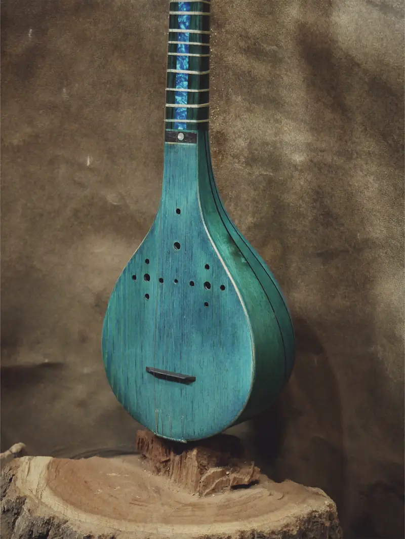 A turquoise setar on a wooden stand.